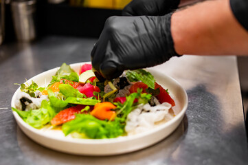 chef hands cooking Fresh sashimi salad with salmon fish, tuna and vegetables on kitchen