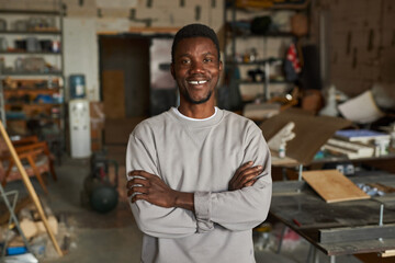 Obraz premium Waist up portrait of confident black man smiling at camera in workshop, copy space