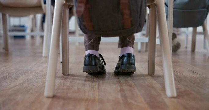 Floor, class and feet of a student with anxiety, exam stress or adhd while learning. Restless, low and a child or teenager at a desk with a nervous leg for a test, education or studying at a school