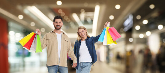 Happy couple with shopping bags walking in mall, banner design