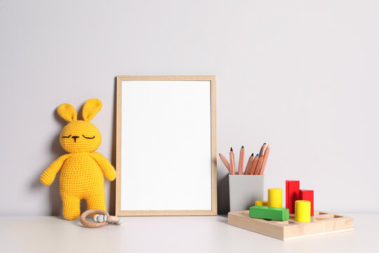Empty square frame, stationery and different toys on white table
