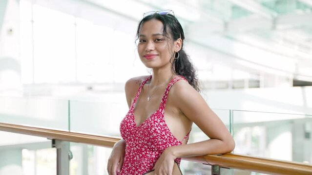 Beautiful asian woman standing on balcony with city view. Wearing red dotted summer dress