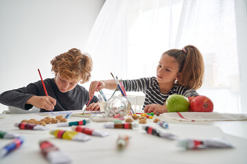 Children painting together at table