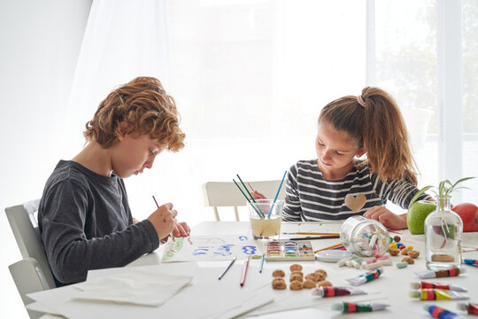 Brother and sister drawing sitting at table