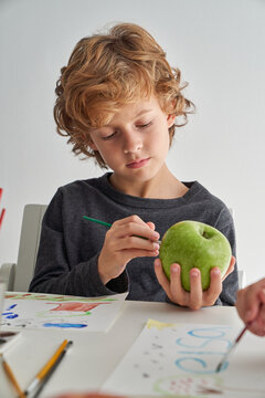 Focused boy painting on apple