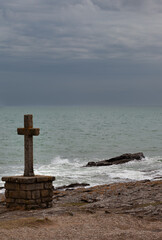 Maritime landscape with a granite religious cross. The Atlantic coast cut out in bad weather with a granite Catholic cross in the foreground.