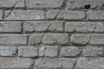 Uneven surface of old and scratched grey brick wall