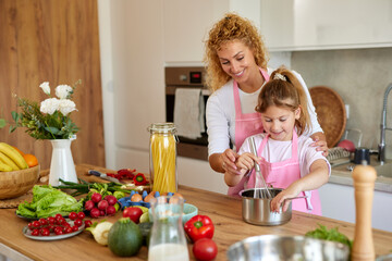 Mother and daughter preparing tasty food at home