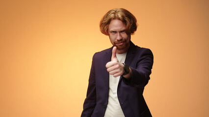 Handsome unshaven bearded young guy in a business suit, isolated on a yellow background in the...