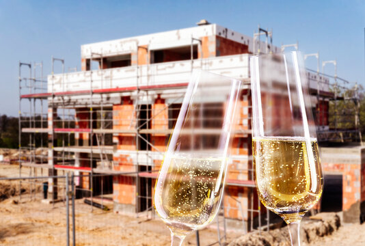 Champagne glasses and construction site with shell of a family house