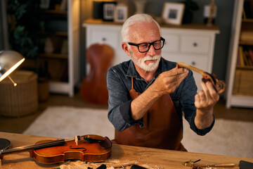 Senior violin maker repairing a violin