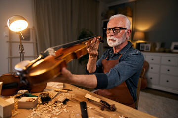 Senior violin maker repairing a violin