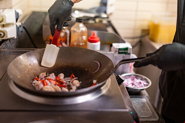 Professional chef cooking chicken food in wok pan on kitchen