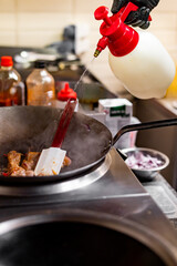 Professional chef cooking chicken food in wok pan on kitchen