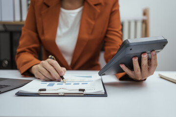 Fototapeta premium Close up hands of woman in brown formal suit checking bills, taxes, bank account balance, using calculator, Personal Checking, Empower Checking, Personal Savings, Certificates, IRAs, Money Market