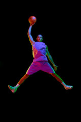 Full-length of competitive young man in motion during basketball game, jumping with ball against...