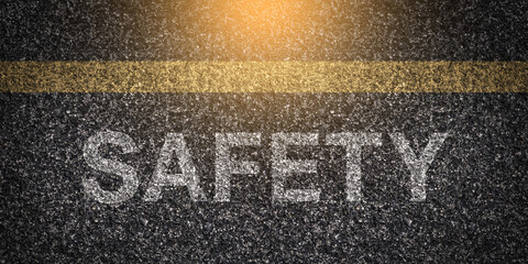 Textured asphalt with "Safety" text on the road under a yellow line, rough surface of tarmac with the word "Safety" written, caution message on pavement, road safety concept