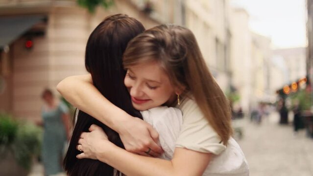 Happy young girls friends or sisters met and hugged tightly after not seeing each other for long time outdoors Smiling women enjoying beautiful day together after separation at city Friendship concept