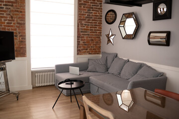 photo of the interior of a modern living room. gray sofa, coffee table in front of a large window