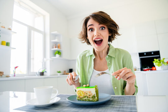 Photo of positive shocked girl wear green shirt cutting fresh piece of cake indoors kitchen room