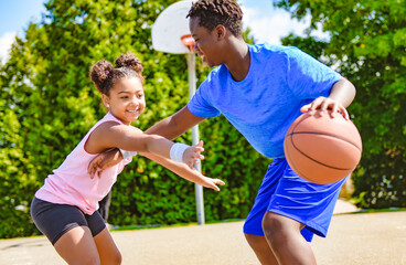 Portrait of brother and sister basketball player standing at basketball court with ball