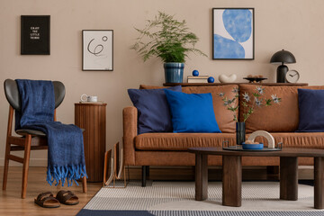Interior design of cozy living room interior with mock up poster frame, brown sofa, wooden consola, blue pillows, plaid, orange pouf, patterned rug and personal accessories. Home decor. Template.