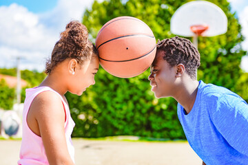 Portrait of brother and sister basketball player standing at basketball court with ball