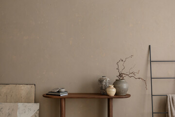 Minimalist composition of living room interior with copy space, wooden console, black ladder, gray vase with branch, books, beige wall and personal accessories. Home decor. Template.