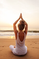 Woman practicing yoga by the ocean at dawn - 642084952