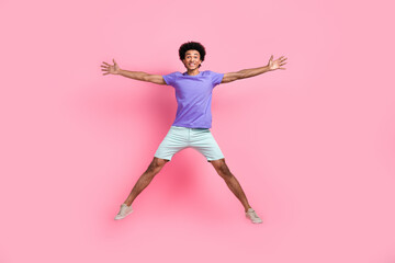 Fototapeta na wymiar Full size photo of good mood guy wear blue t-shirt white stylish pants flying jumping in star pose isolated on pink color background