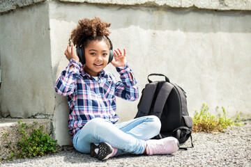 child going back to school with a backpack listening music