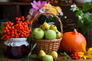 Naklejka na ściany i meble Autumn still life with pumpkin. Flowers and apple harvest in a wicker basket, orange ripe pumpkins on the table