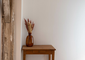 Des pampas, plumeaux séchés dans un vase sur une table en bois en décoration d'une maison neuve