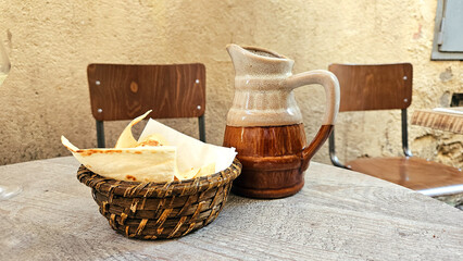 A jug with slices of lavash, bread on the table. In warm colors, in the style of historical, in the atmosphere of ancient architecture
