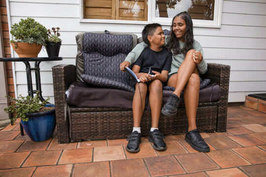 Aboriginal girl and young Aboriginal boy sitting together - motion blur on girl