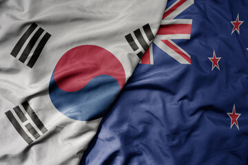 big waving national colorful flag of south korea and national flag of new zealand .