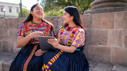 Friends chat, one of them holds a smart device in her hand.