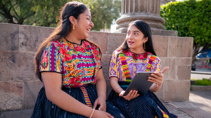 Two beautiful women talk sitting in their city park.