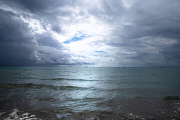 Beautiful dark evening sea and sky with dark clouds through which light passes.
