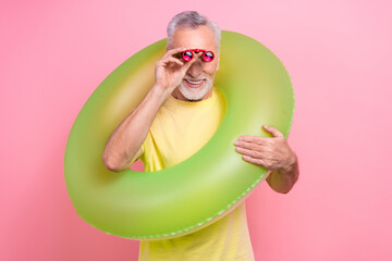 Photo of professional lifeguard senior grey hair man watching how people chill swimming pool binoculars isolated on pink color background
