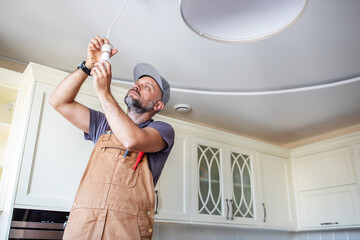 electrician screws a lamp at home in the kitchen - 642097561