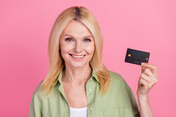 Fototapeta premium Close up photo of cheerful rich lady wear trendy khaki clothes hand hold recommend bank plastic card isolated on pink color background