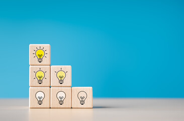Innovation and creativity idea concept. Teamwork and brainstorming for business start-up creative ideas and solving problems. Wooden blocks with glowing light bulb icons with dim brightness levels. © RerF
