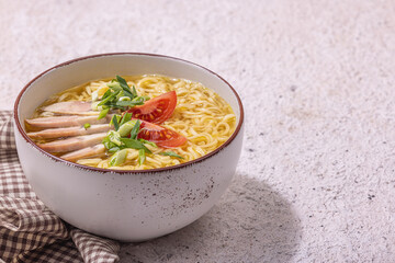 Spicy noodles with beef broth. Hot dish, cutlery, hard light, dark shadow. Stone concrete background
