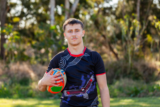 Portrait of Aussie teenager with footy game ball tucked under arm