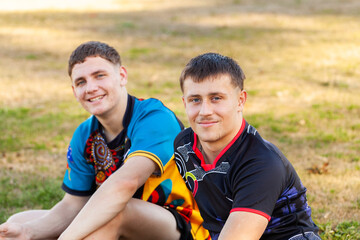 Aboriginal teen sport players sitting on side-lines of footy field