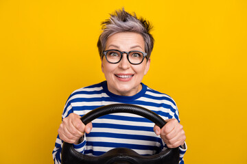 Photo of excited lady pensioner wear trendy clothes riding car pass exam driving school isolated on yellow color background