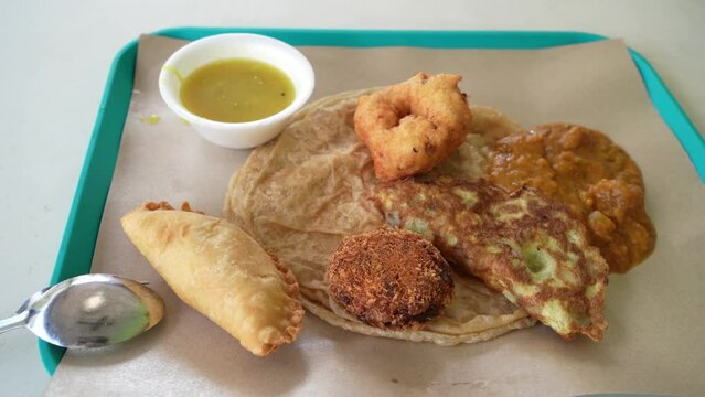 Indian food roti canai with dhal masala vadai, vada, fried egg and curry puff with dhal.