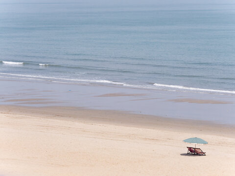 Deck chairs and parasol on empty beach