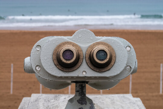Vista de una playa en oto&ntilde;o lloviendo con un catalejo en primer t&eacute;rmino.